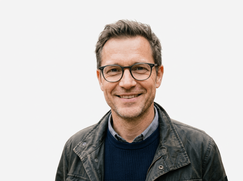 Middle-aged man with glasses smiling outdoors in a park